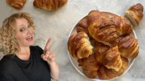 Piatto con cornetti sfogliati fatti in casa su sfondo chiaro accanto a una persona sorridente.