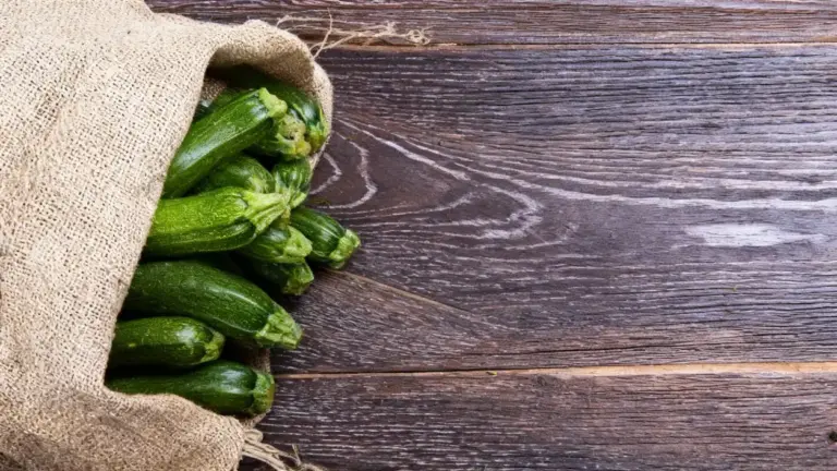 Zucchine fresche in un sacco di juta su fondo in legno