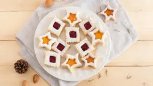 Biscotti di Natale a forma di stella e quadrato con marmellata su un piatto bianco