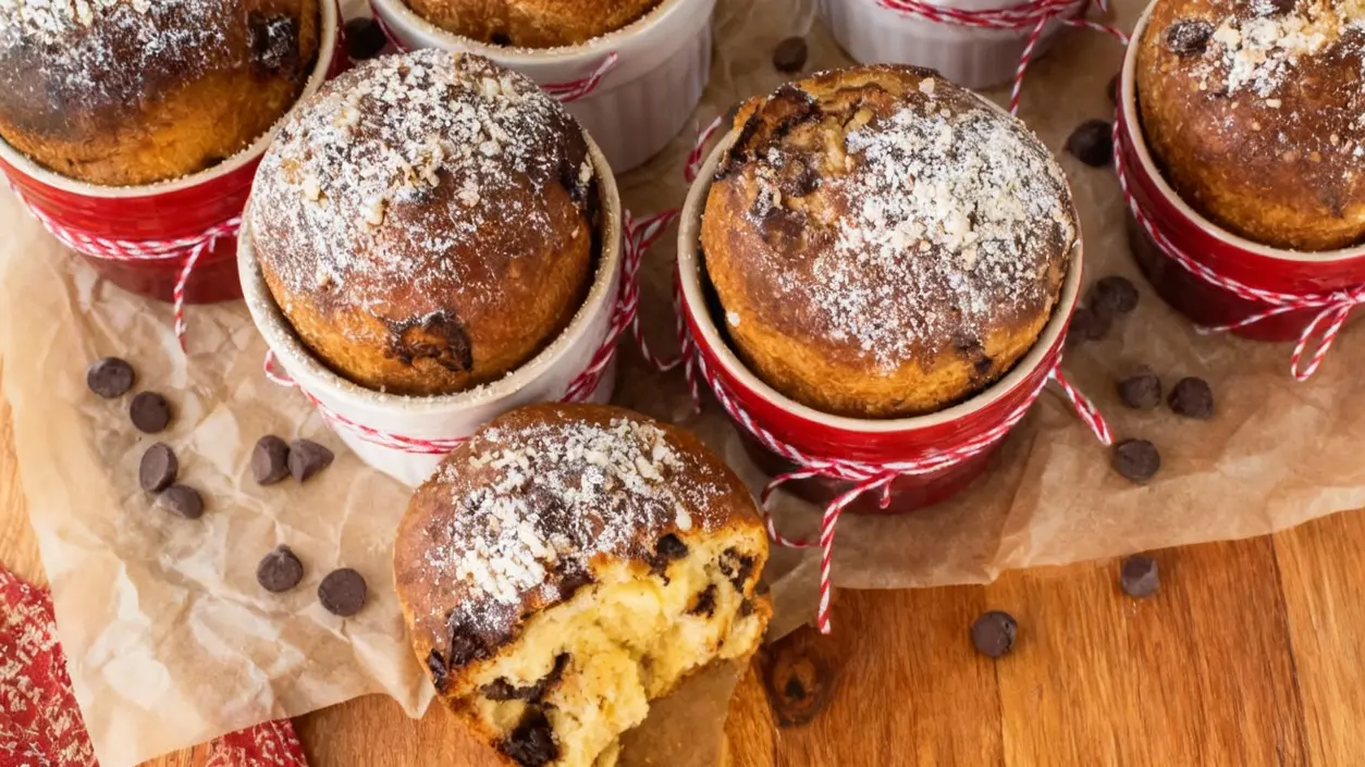 Dolci soffici in cocotte rosse con gocce di cioccolato e zucchero a velo