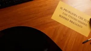 Scrivania in legno con foglio giallo e penna, vicino a una tastiera.