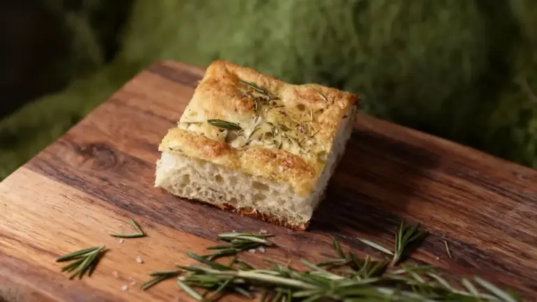 Fetta di focaccia soffice con rosmarino su tagliere di legno