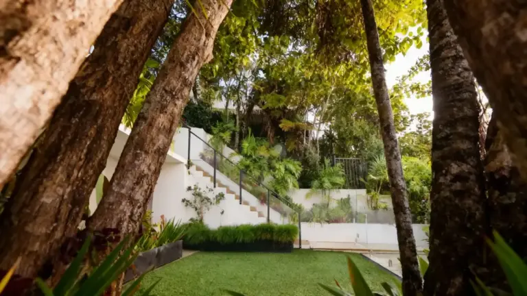 Giardino curato con prato verde, alberi e piante ornamentali vicino a una scalinata esterna