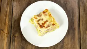 Una porzione di lasagna chiara e cremosa servita su un piatto bianco