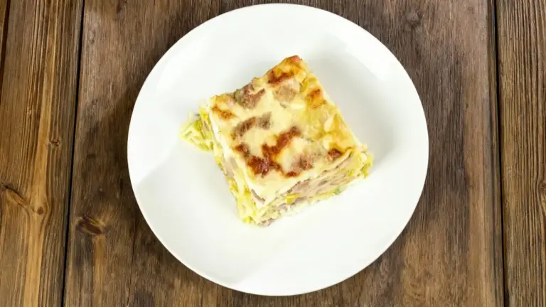 Una porzione di lasagna chiara e cremosa servita su un piatto bianco