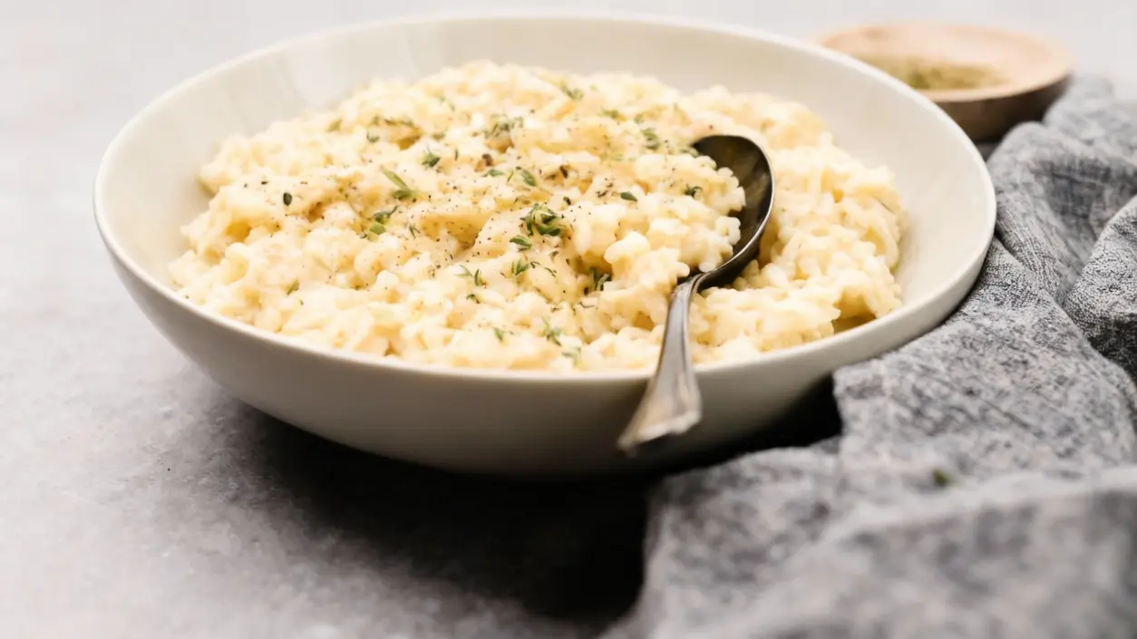 Un piatto di risotto cremoso servito con un cucchiaio, guarnito con erbe aromatiche