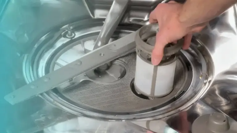 Una mano rimuove il filtro da una lavastoviglie per pulirlo facilmente