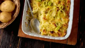 Sformato rustico di patate e porri gratinato in teglia bianca con cucchiaio