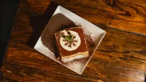 Dessert al cacao su piatto quadrato bianco con decorazione in crema e fogliolina